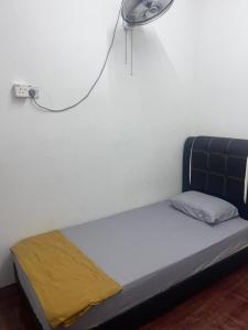 a bed in a room with a fan on the wall at NR Guest House in Kangar +3 photos