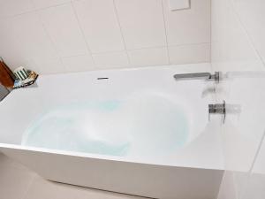 a white bath tub in a white bathroom at 2BR Retro Luxe Family Hideaway in Gold Coast +28 photos