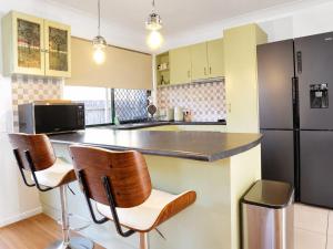 a kitchen with two bar stools and a black refrigerator at 2BR Retro Luxe Family Hideaway in Gold Coast