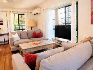 a living room with a couch and a tv at 2BR Retro Luxe Family Hideaway in Gold Coast