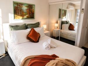 a bedroom with a large white bed with a mirror at 2BR Retro Luxe Family Hideaway in Gold Coast