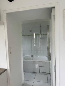 a white bathroom with a tub and a shower at Ground-Floor Apartment With private Garden in Étampes