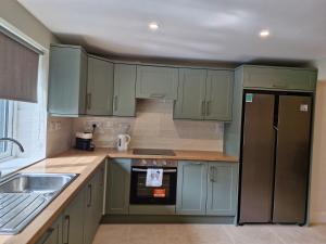 a kitchen with green cabinets and a sink and a refrigerator at The old B&B in Killucan