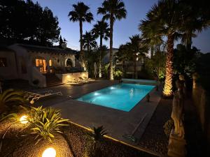 a swimming pool in front of a house with palm trees at Casa El Mirador in Calpe