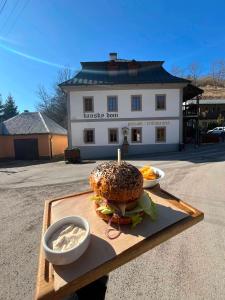 a hamburger on a cutting board with two bowls of dip at Penzión Banský dom in Banská Štiavnica