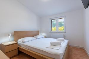 a bedroom with a bed with white sheets and a window at Villa Omaha in Vekići +47 photos