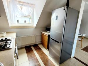 a kitchen with a refrigerator and a window at Apartament Nad Lodziarnią in Wydminy