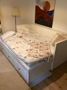 a white bed in a bedroom with a painting on the wall at Erikslund in Hurva