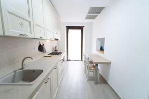 a white kitchen with a sink and a counter at Bidderosa in Orosei