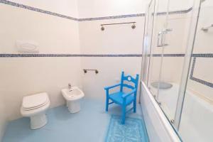 a bathroom with a toilet and a blue chair at Bidderosa in Orosei