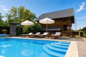 a pool with chairs and umbrellas next to a cabin at Wild River in Neporotovo