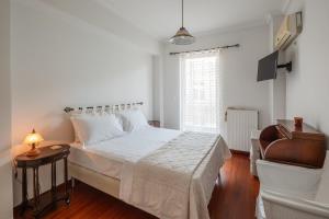 a white bedroom with a bed and a chair at Jenny's Appartment in Faraí +12 photos