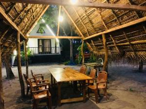 a wooden table and chairs under a thatched roof at Sambu Cabana Panama in Panama