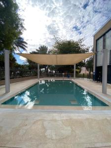 a swimming pool with a large umbrella over it at SPNI Ein Gedi Field School in Ein Gedi