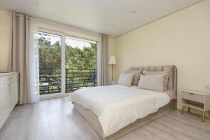 a white bedroom with a bed and a large window at 2rest in Palanga