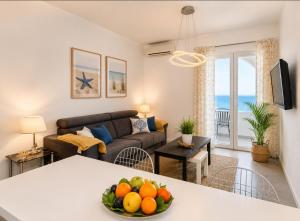 a living room with a couch and a table with fruit at Villa Tamaris on the beach in Podstrana