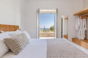 a bedroom with a white bed and a large window at Melora Villas Paros in Aliki +38 photos