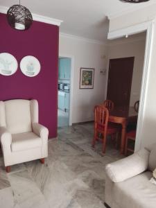 a living room with a white chair and a table at Piso de 3 habitaciones en el centro de Punta Umbria recién renovado! in Punta Umbría +1 photo
