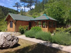 a wooden cabin with a green roof in a garden at Air Zaovine in Bajina Bašta