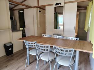 a kitchen with a wooden table and white chairs at Camping de Tournus - Drole de cabane in Tournus