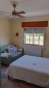 a bedroom with a bed and a couch and a window at Casa Rural Barxa in Monforte de Lemos