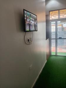 a flat screen tv on a wall with a green floor at Nelca Executive Lodge in Mwanza
