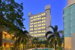 a tall building with palm trees in front of it at Boulevard9, Nadiad - IHCL SeleQtions in Nadiād
