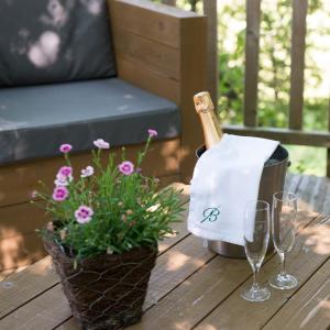 a bottle of champagne and glasses on a table with flowers at Cabane du Bois des Nauzes in Seyches