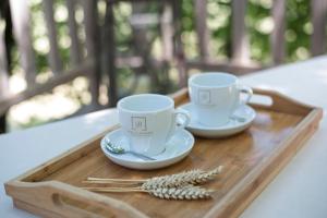 two cups and saucers sitting on a wooden tray at Cabane du Bois des Nauzes in Seyches