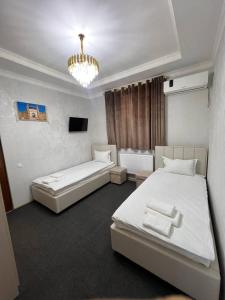 a bedroom with two beds and a chandelier at Sobirjon Guest House in Khiva
