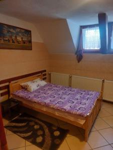a bedroom with a wooden bed with a purple mattress at Hangya panzió in Târgu Secuiesc +36 photos