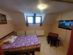 a bedroom with a bed and a table and a tv at Hangya panzió in Târgu Secuiesc