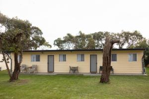 a yellow house with a table and chairs in a yard at KI Caravan Park, Kingscote in Kingscote