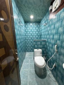 a bathroom with a toilet and blue tiled walls at Nahor Regency in Guwahati