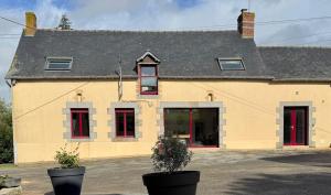 a large yellow building with red doors and windows at Gite du haras in Erbrée
