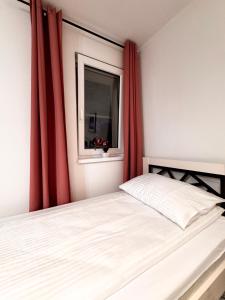 a bedroom with a bed with red curtains and a window at Domek pod Jabłonią in Barzowice