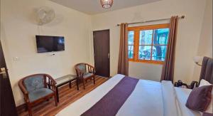 a bedroom with a bed and a desk and a tv at The Woods Boho in Nainital