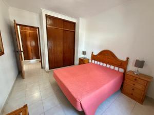 a bedroom with a pink bed and a wooden door at Casa Nau B in Armação de Pêra