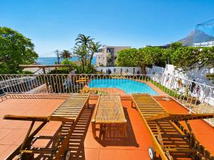 a group of benches sitting next to a swimming pool at SeaViu Camps Bay in Cape Town