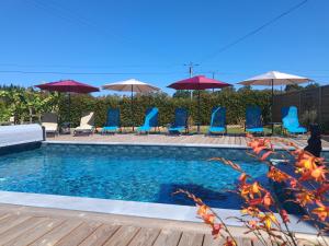 a swimming pool with blue chairs and umbrellas at gîte en campagne Lamégritnière in Mégrit
