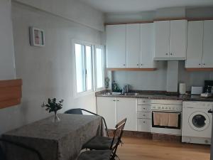 a kitchen with a table and a kitchen with white cabinets at Piso 4 dormitorios playa sada in Sada +20 photos