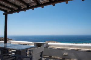 a table and chairs on a balcony with the ocean at Villa Anemelia Tinos in Agios Ioannis