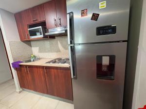 a stainless steel refrigerator in a kitchen with wooden cabinets at Departamento 68 river 2 in Guayaquil