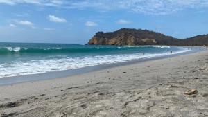 a beach with people in the water and a mountain at La Fogata Bungalows in Machalilla +41 photos