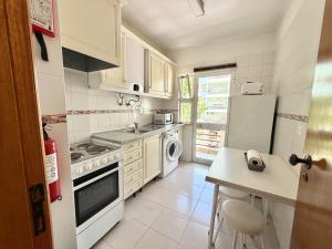 a kitchen with a stove and a sink and a refrigerator at Casa Caravela C in Armação de Pêra