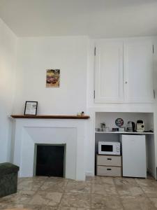 a white kitchen with a fireplace and a microwave at Chez Rémi in Écommoy