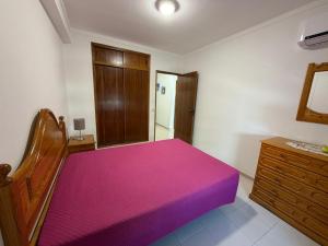 a bedroom with a pink bed and a wooden dresser at Casa Caravela C in Armação de Pêra +10 photos