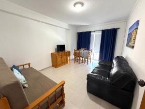 a living room with a black leather couch and a television at Casa Caravela C in Armação de Pêra