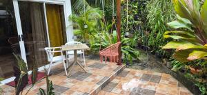 a patio with a table and a chair and some plants at Hinevai LODGE in HUH
