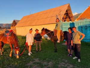 a group of people standing around a man on a horse at Asylbek Guesthouse horseback riding tours in Kyzart +36 photos